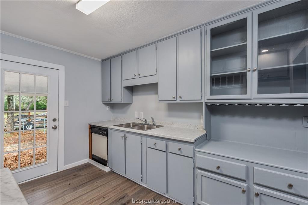 3755 West Villa Maria Road Bryan, TX 77807 - Photo 11 of 26 Kitchen with gray cabinetry, light countertops, glass insert cabinets, dark wood-style floors, and crown molding