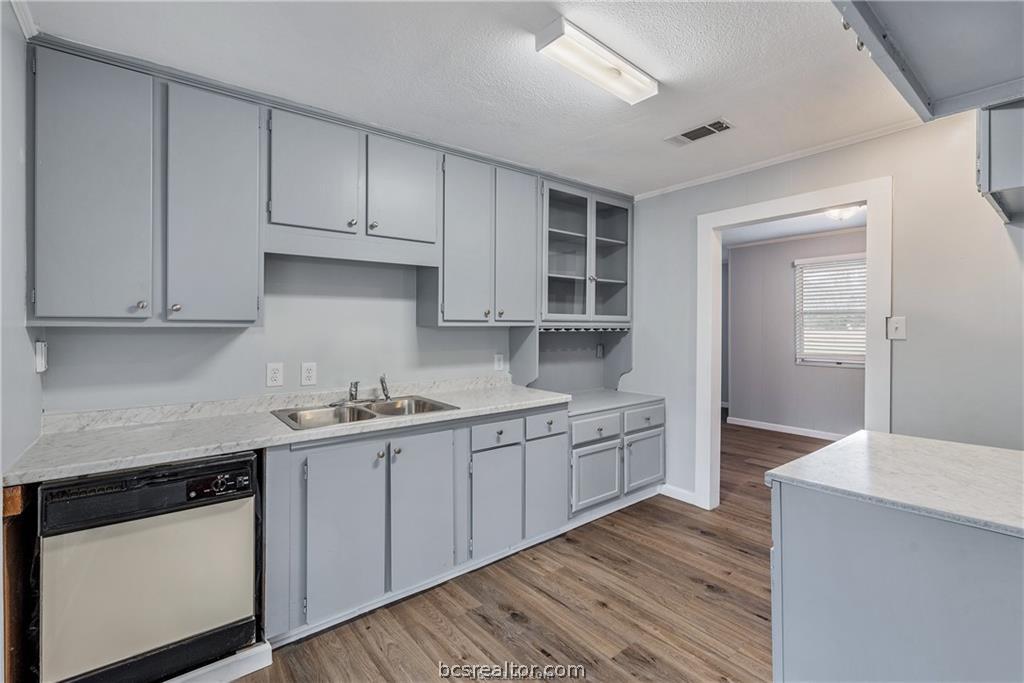 3755 West Villa Maria Road Bryan, TX 77807 - Photo 12 of 26 Kitchen featuring gray cabinets, white dishwasher, light countertops, a textured ceiling, and light wood-type flooring