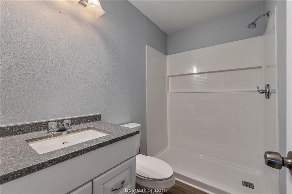 3755 West Villa Maria Road Bryan, TX 77807 - Photo 13 of 26 Full bathroom featuring vanity, a textured wall, and a shower stall