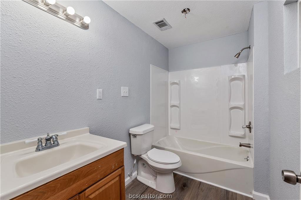 3755 West Villa Maria Road Bryan, TX 77807 - Photo 16 of 26 Full bath featuring a textured wall, vanity, washtub / shower combination, dark wood-style floors, and a textured ceiling