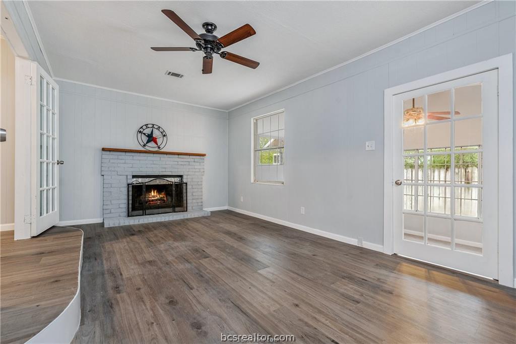 3755 West Villa Maria Road Bryan, TX 77807 - Photo 23 of 26 Second living room featuring ceiling fan, ornamental molding, dark wood-style floors, and a brick fireplace