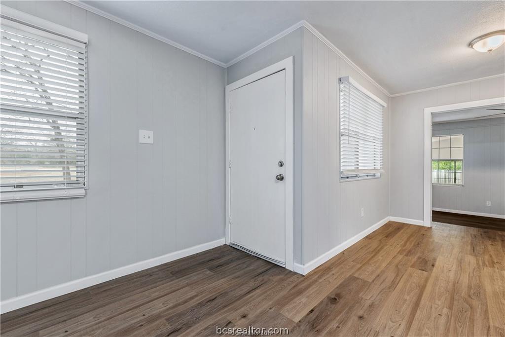 3755 West Villa Maria Road Bryan, TX 77807 - Photo 4 of 26 Entryway with crown molding, dark wood-type flooring, and wood walls