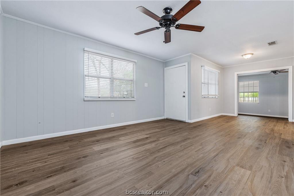 3755 West Villa Maria Road Bryan, TX 77807 - Photo 5 of 26 Unfurnished living room with ceiling fan, dark wood-type flooring, plenty of natural light, and crown molding