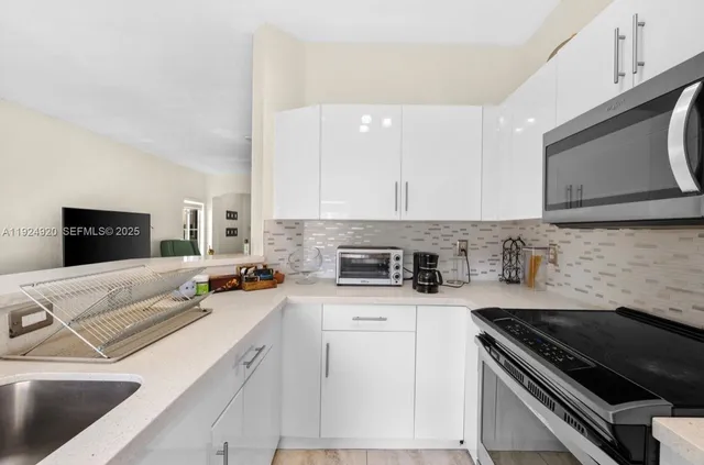 a kitchen with granite countertop a sink a stove and cabinets