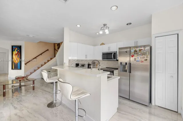 a kitchen with stainless steel appliances kitchen island granite countertop a refrigerator and cabinets