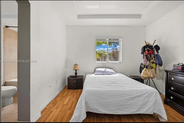 a bedroom with a bed a painting on the wall and a dresser