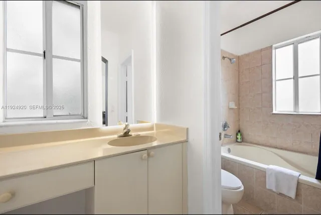 a bathroom with a granite countertop sink and a bathtub with shower