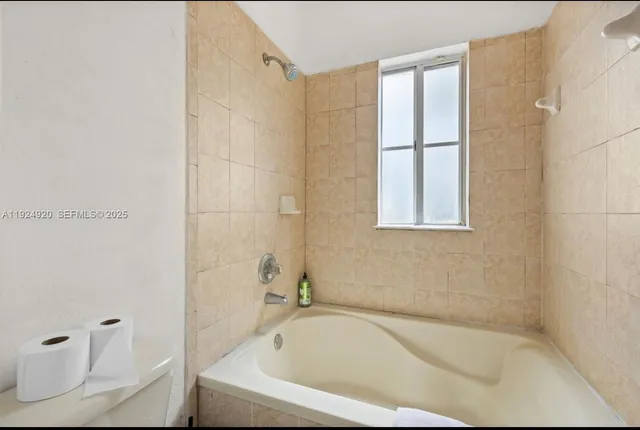 a white bath tub sitting next to a white toilet and vanity