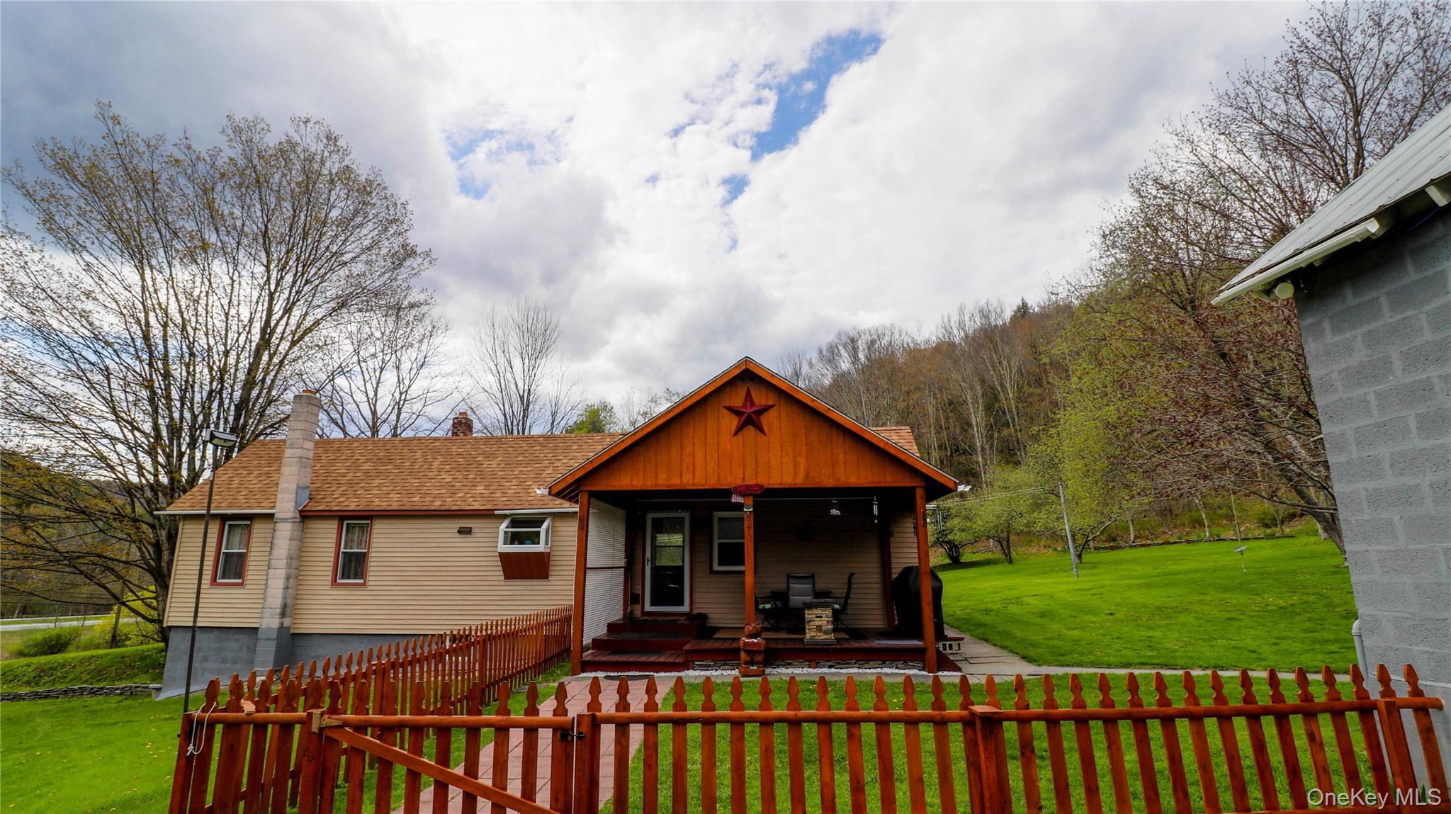 11 Hood Road Roscoe, NY 12776 - Photo 2 of 31 Ranch-style residence featuring a prominent covered front porch with exposed wood beams, a red star decorative element, and a wooden deck