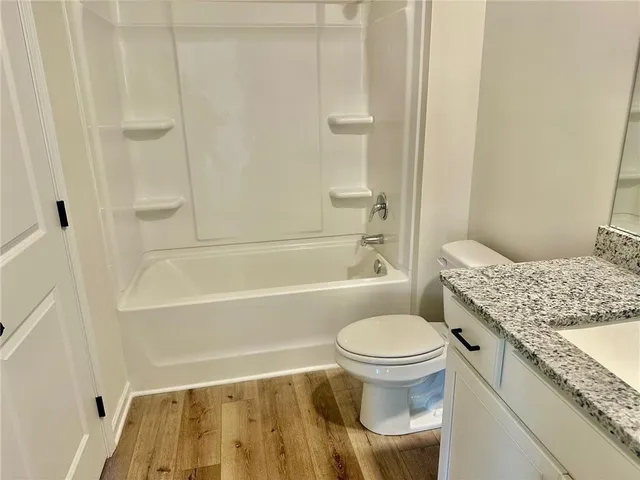 a bathroom with a granite countertop toilet a sink and a bathtub