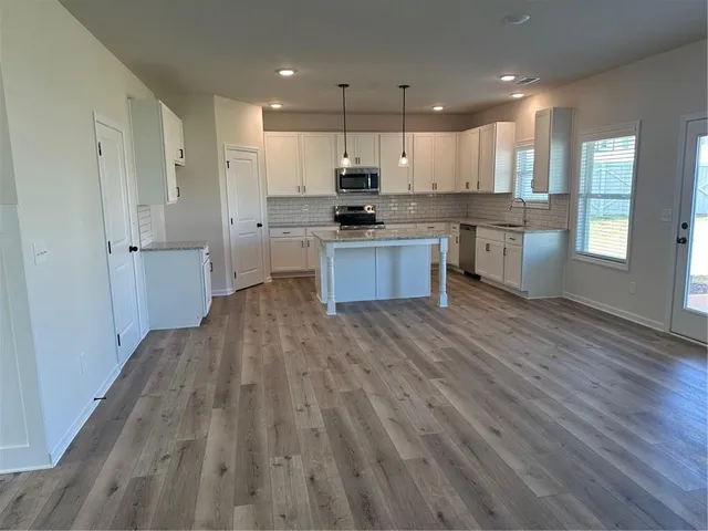 a large kitchen with stainless steel appliances granite countertop a large counter top a stove and a refrigerator