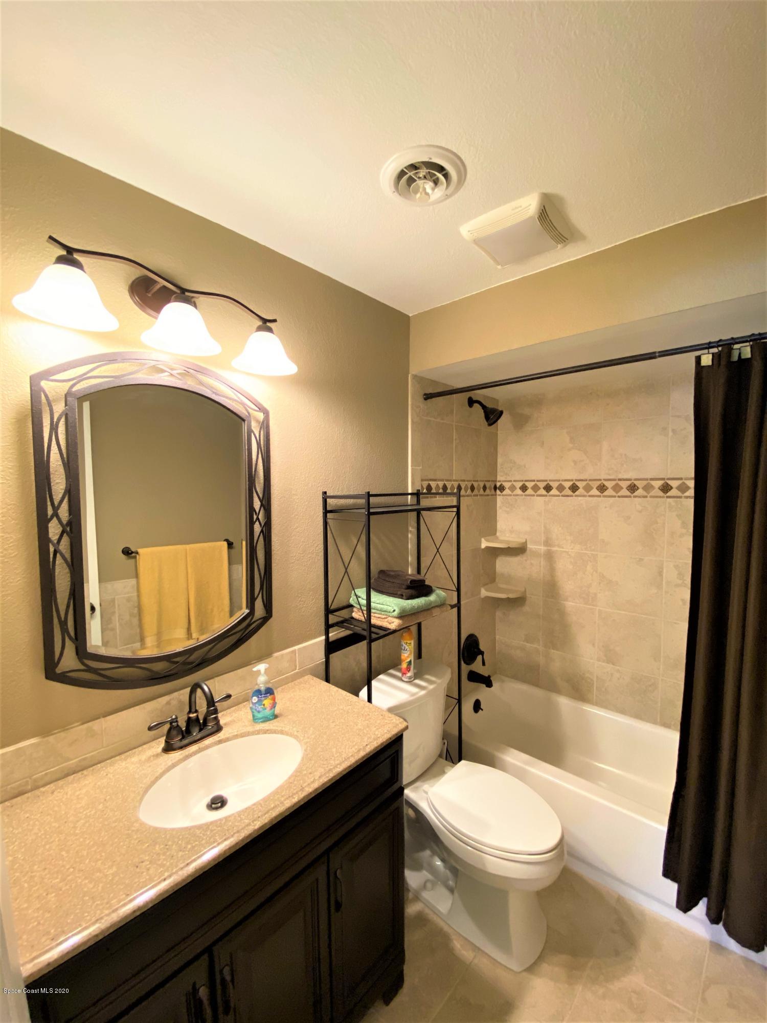 175 Tiki Drive Merritt Island, FL 32953 - Photo 11 of 15 a bathroom with a toilet a sink and a mirror