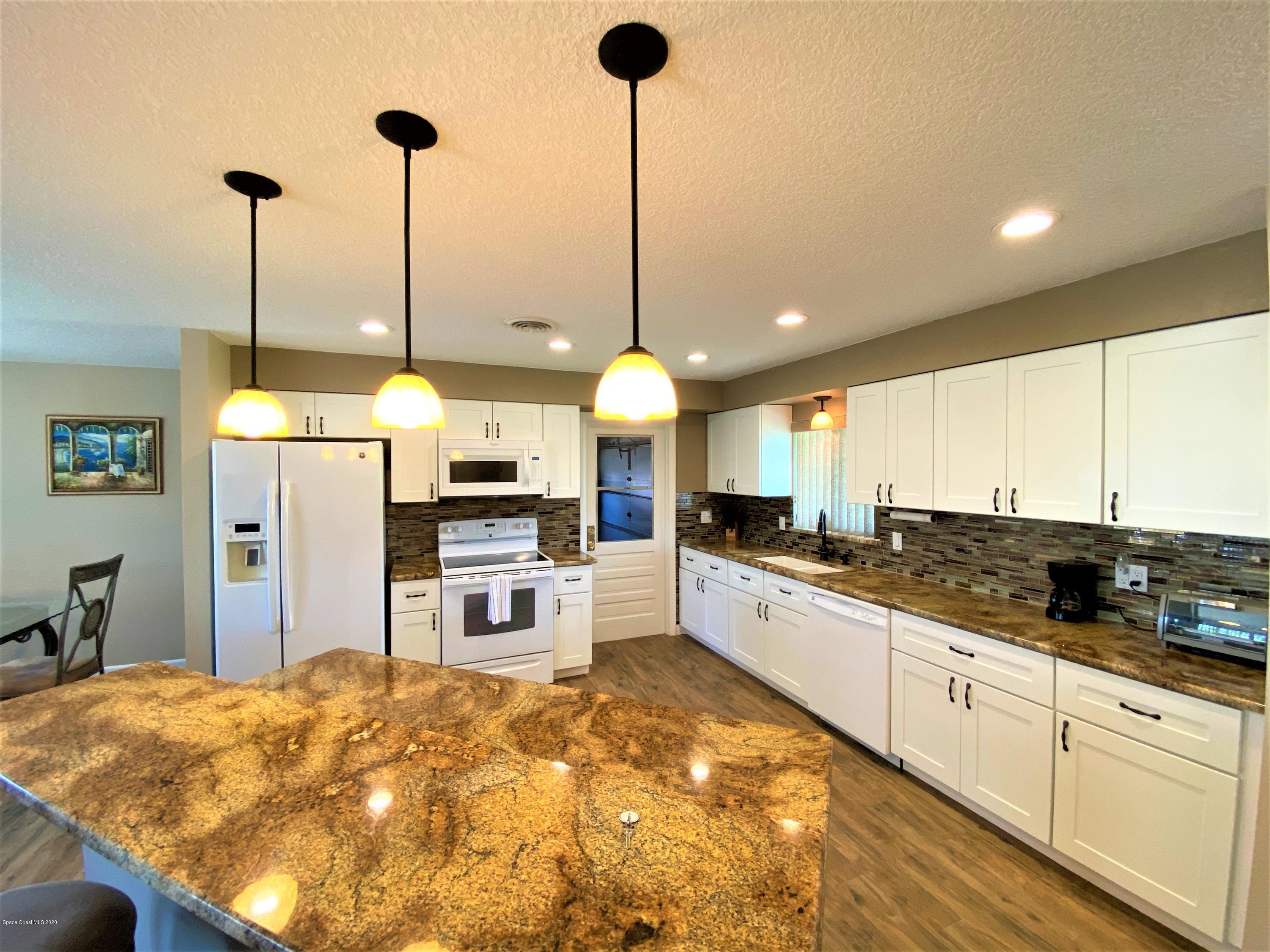 175 Tiki Drive Merritt Island, FL 32953 - Photo 3 of 15 a kitchen with stainless steel appliances kitchen island granite countertop a table and chairs in it