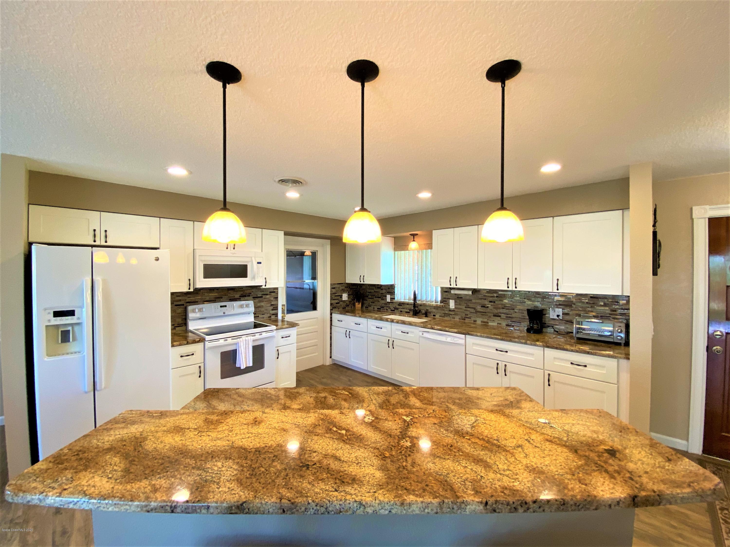 175 Tiki Drive Merritt Island, FL 32953 - Photo 4 of 15 a kitchen with stainless steel appliances kitchen island granite countertop a sink a counter space and cabinets