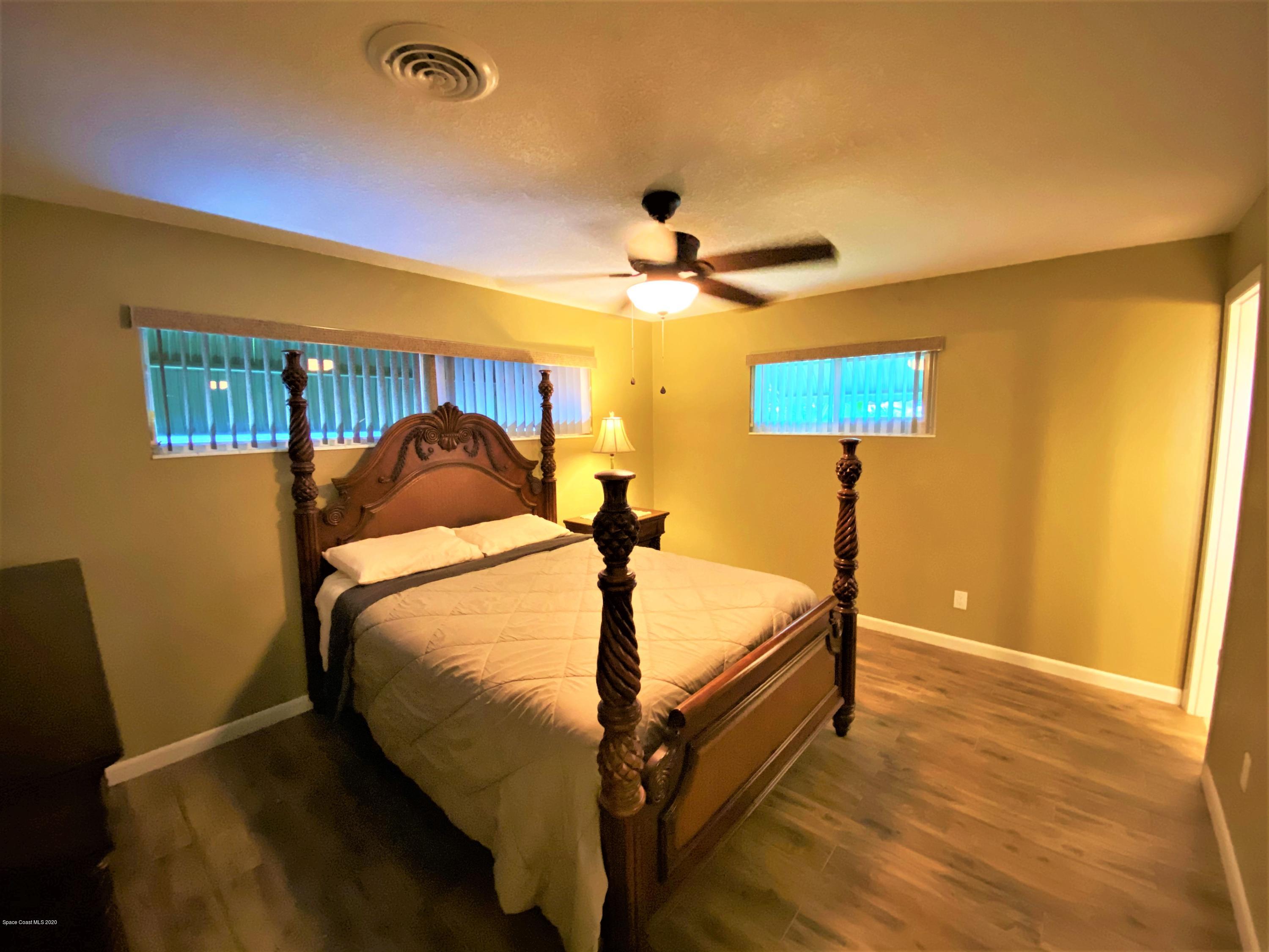 175 Tiki Drive Merritt Island, FL 32953 - Photo 8 of 15 a bed sitting in a bedroom next to a lamp
