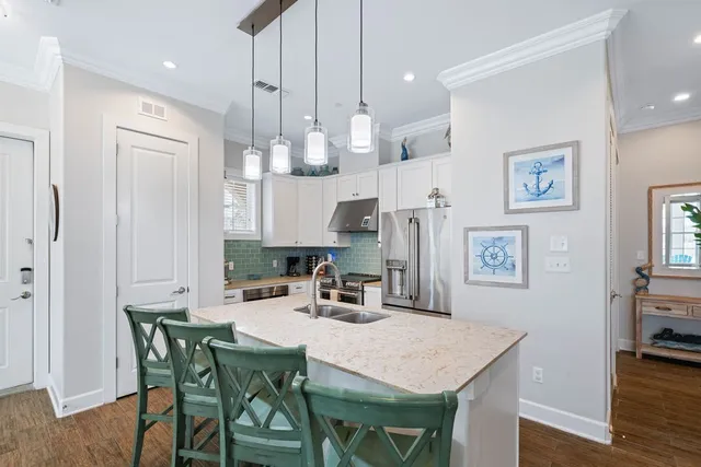 a kitchen with stainless steel appliances granite countertop a dining table chairs and a refrigerator a sink with wooden floor