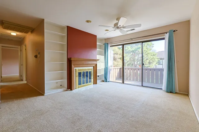 a view of an empty room with chandelier fan and a fireplace