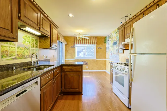 a kitchen with stainless steel appliances granite countertop a sink and wooden cabinets