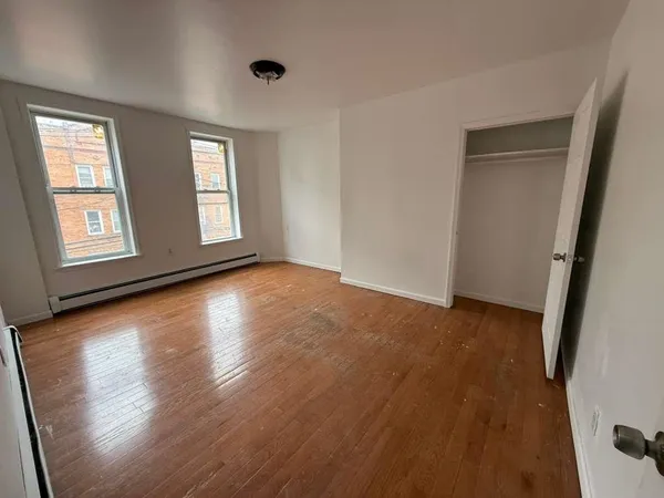 a view of an empty room with wooden floor and window