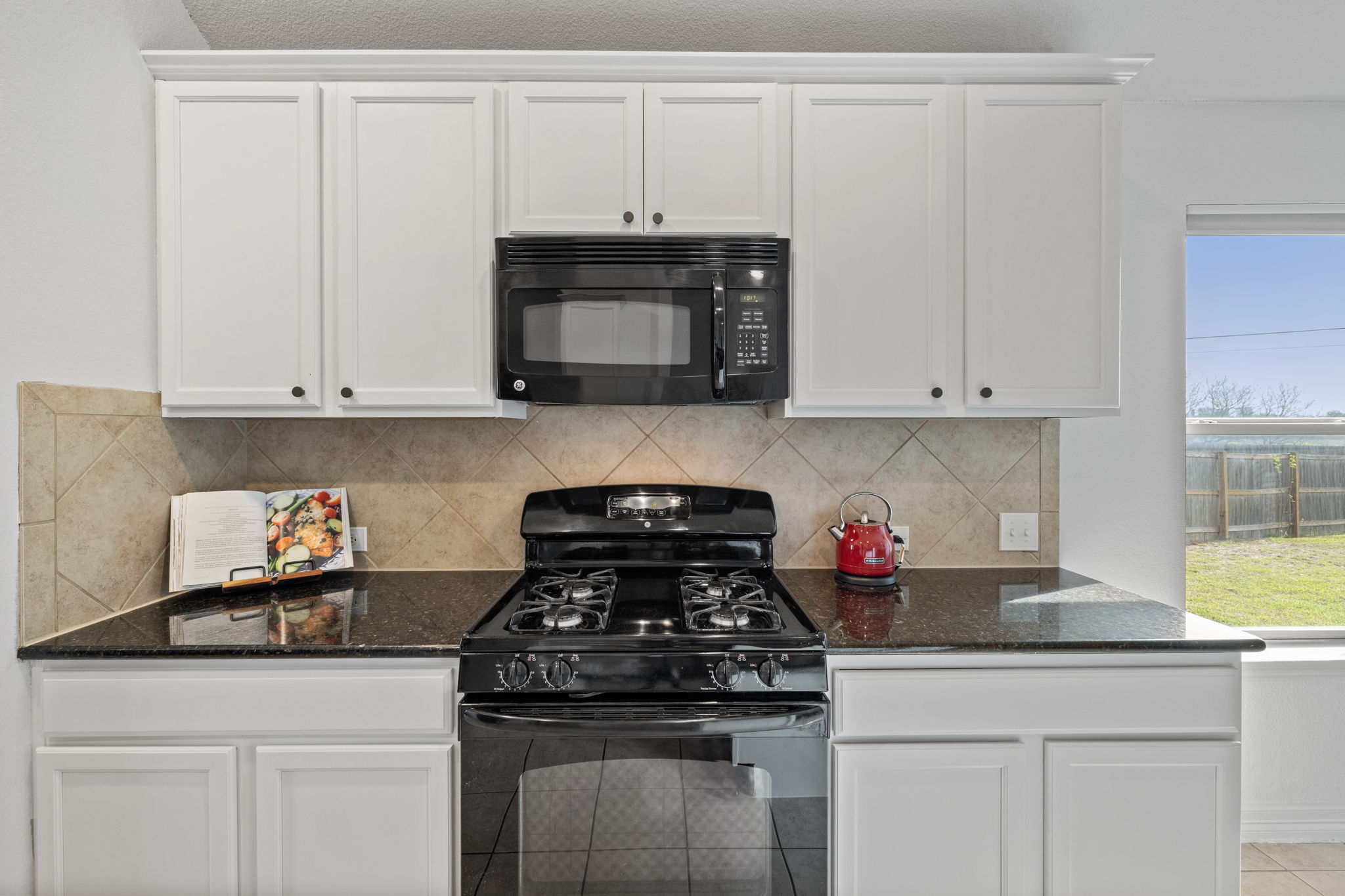 482 Travertine Trail Buda, TX 78610 - Photo 5 of 40 a kitchen with granite countertop white cabinets and stainless steel appliances