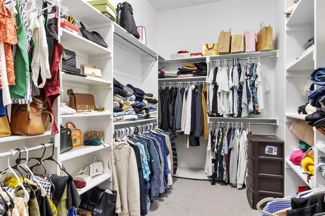 a view of walk in closet with clothes and shoes