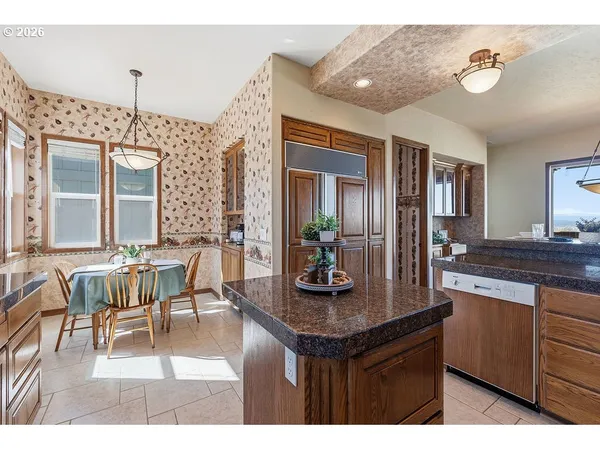 a living room with kitchen island granite countertop furniture a large window and a chandelier