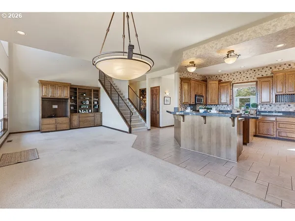a view of a kitchen with kitchen island stainless steel appliances refrigerator stove a dining table and chairs