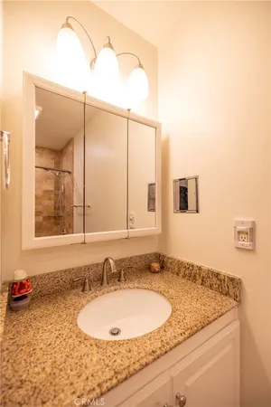 a bathroom with a granite countertop sink and a mirror