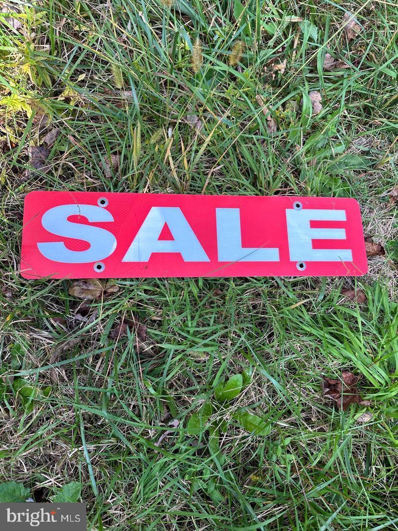 a street sign that is sitting in the grass next to red trees