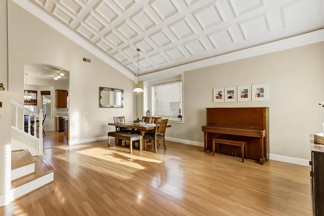 a kitchen with stainless steel appliances granite countertop a stove a sink dishwasher a dining table and chairs with wooden floor