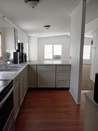 a kitchen with wooden floors appliances and sink