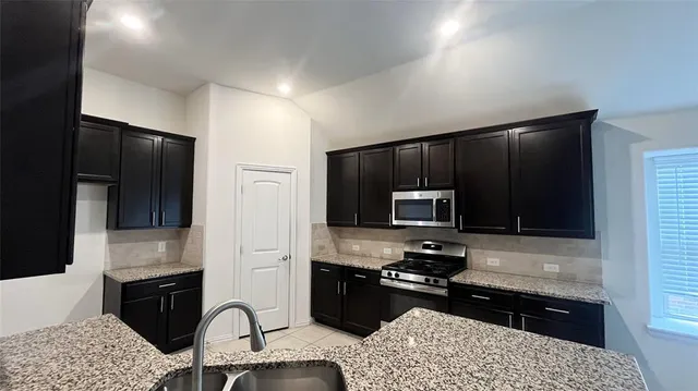 a kitchen with stainless steel appliances granite countertop a sink stove and oven