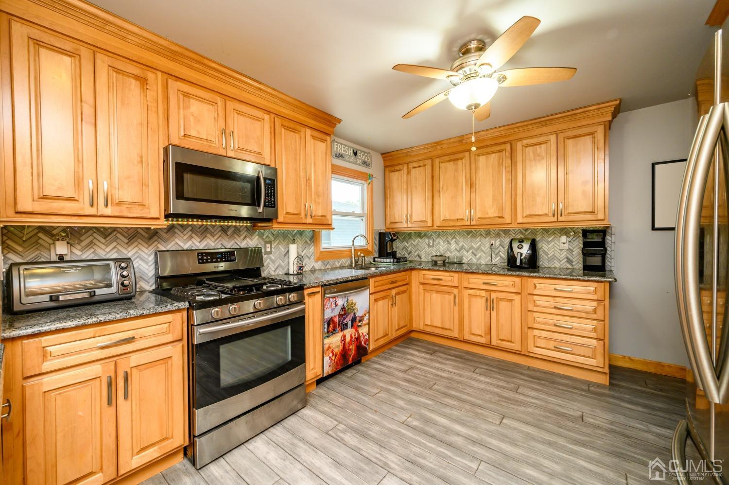 439 Cassville Road Jackson, NJ 08527 - Photo 16 of 45 a kitchen with stainless steel appliances granite countertop a stove top oven a refrigerator a sink and dishwasher with wooden floor