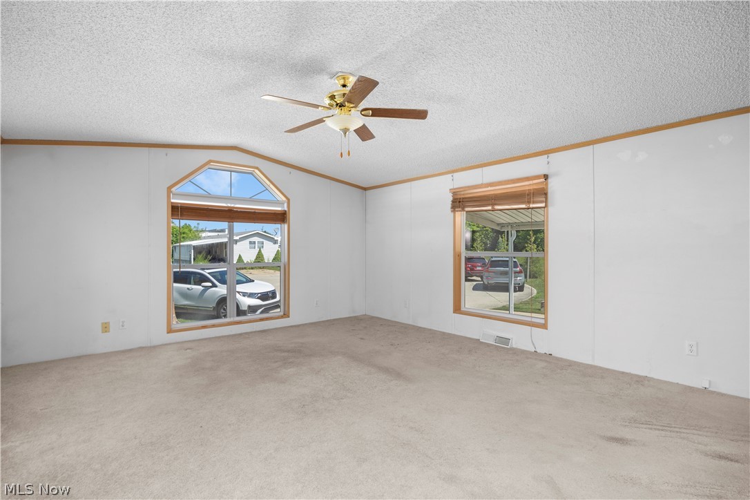 35157 Center Ridge Road, Unit 150 North Ridgeville, OH 44039 - Photo 22 of 33 Carpeted room featuring a ceiling fan, a large arch-top window, and a rectangular window with wood blinds