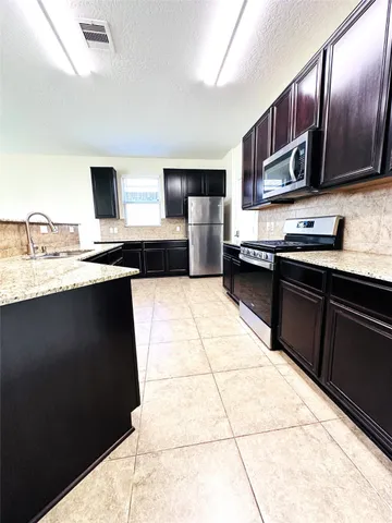a kitchen with stainless steel appliances granite countertop a sink wooden cabinets and granite counter tops