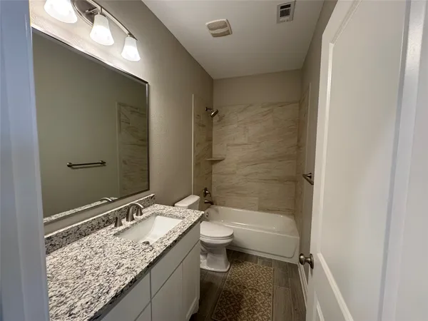 a bathroom with a granite countertop sink toilet and shower