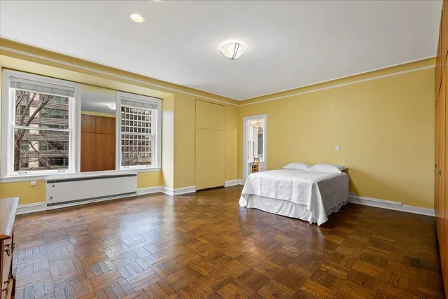 a spacious bedroom with a bed and wooden floor