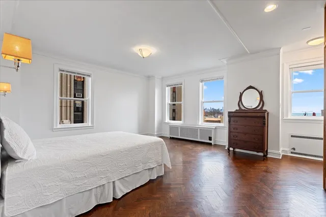 a bedroom with a bed and dresser with wooden floor