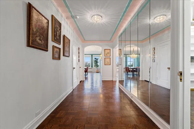 a hallway with wooden floor chandelier and livingroom
