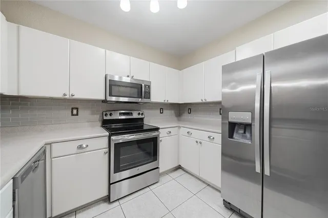 a kitchen with granite countertop white cabinets and stainless steel appliances