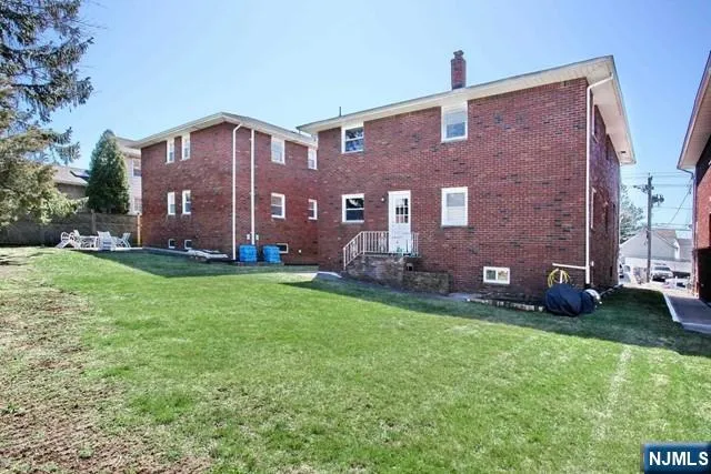 a brick building sitting in front of a big yard with plants and large trees