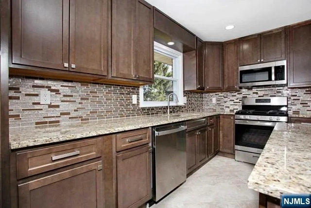 a kitchen with stainless steel appliances granite countertop a sink stove and microwave
