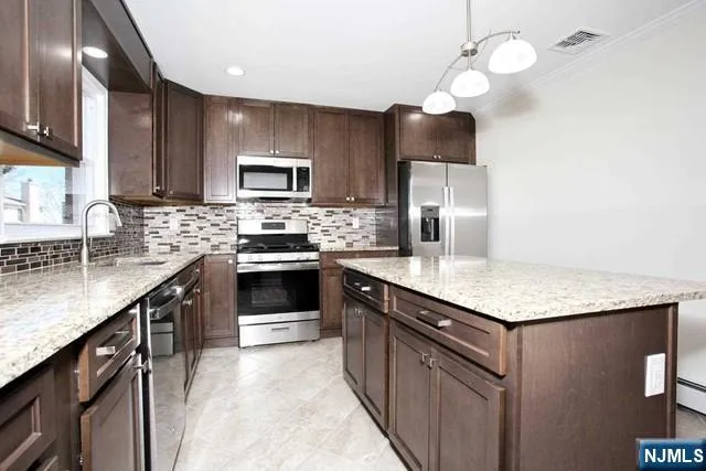 a kitchen with stainless steel appliances granite countertop a stove a sink dishwasher a refrigerator and a oven with wooden floor