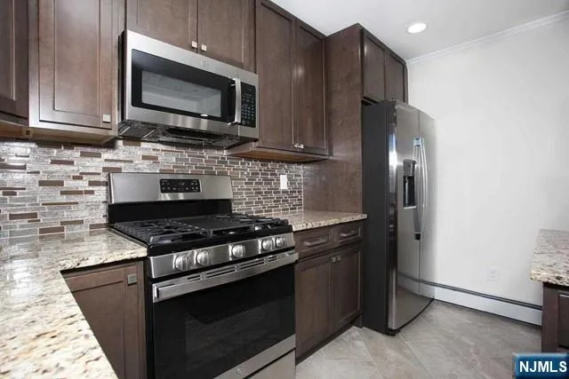 a kitchen with stainless steel appliances granite countertop a stove microwave refrigerator and sink