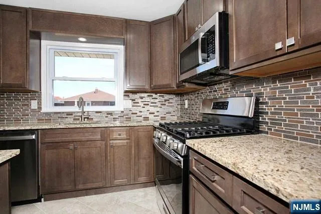 a kitchen with stainless steel appliances granite countertop a sink stove and microwave