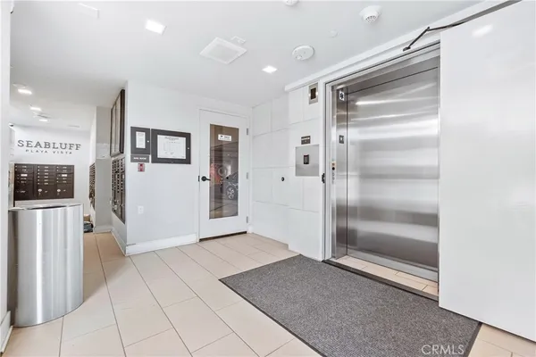 a view of a refrigerator in kitchen and an empty room with wooden floor