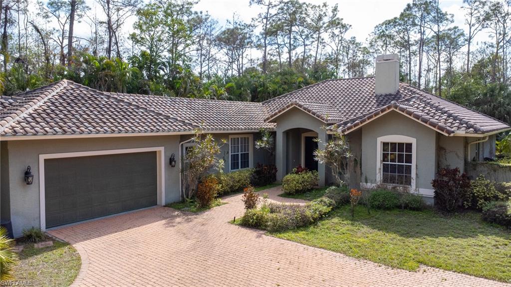 6800 Hunters Road Naples, FL 34109 - Photo 2 of 16 a front view of a house with a garden and plants
