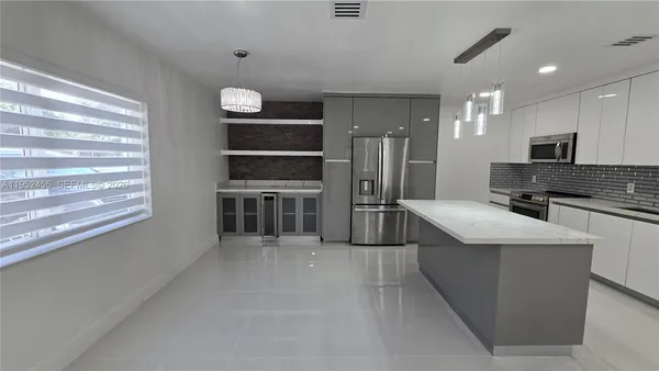 a large kitchen with stainless steel appliances kitchen island granite countertop a refrigerator and a stove top oven