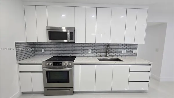 a kitchen with granite countertop white cabinets and stainless steel appliances