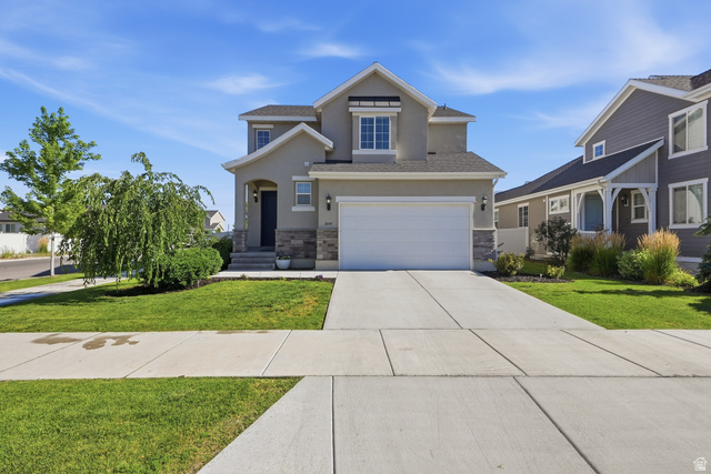 3244 West 1670th Street North Provo, UT 84601 - Photo 2 of 56 Contemporary stucco exterior with a stone veneer accent, featuring a two-car garage, a covered front entry, and mature landscaping